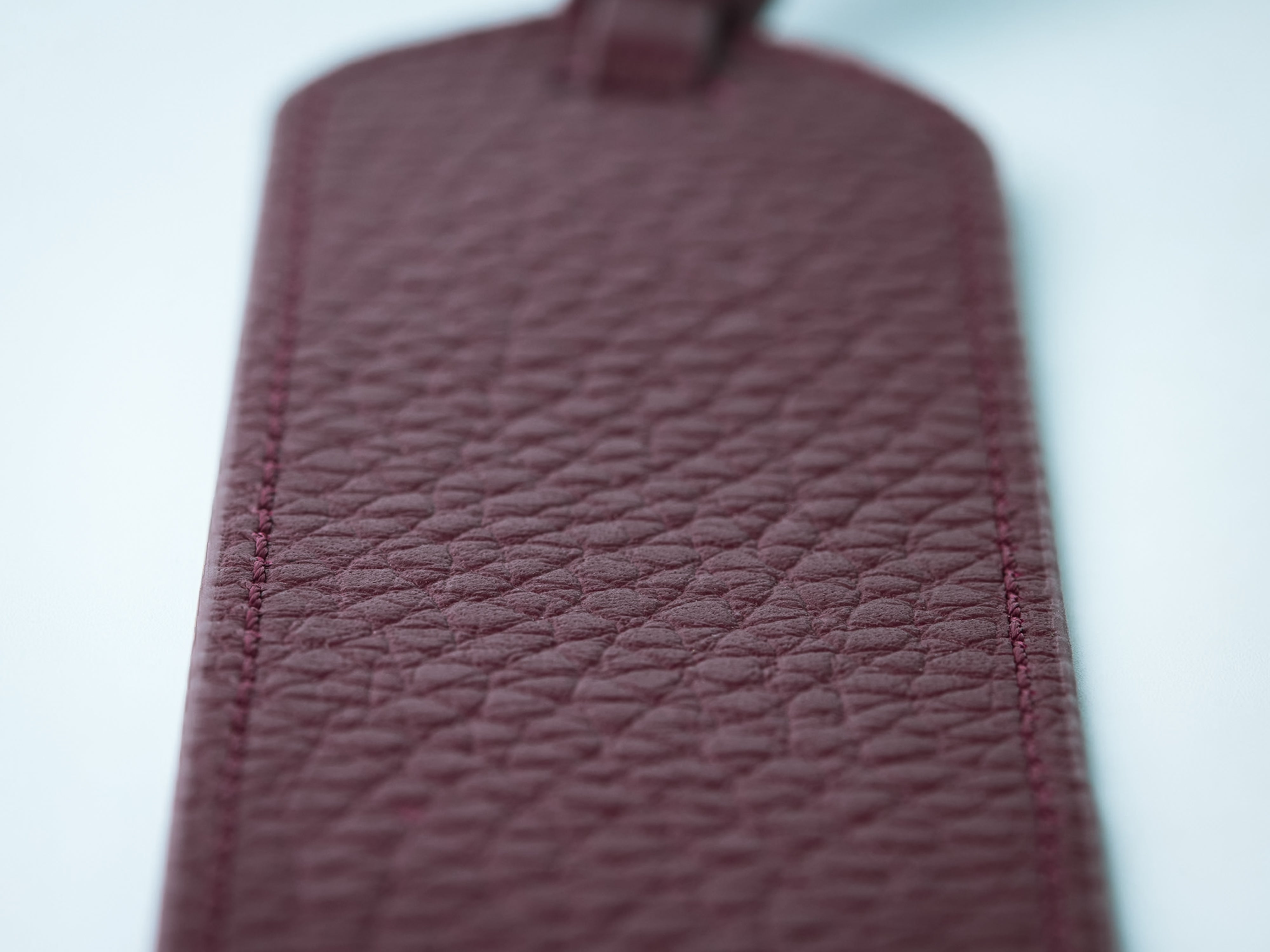 Close-up of a Ubique Italy Burgundy Calf Leather Rectangle Bookmark on a light background