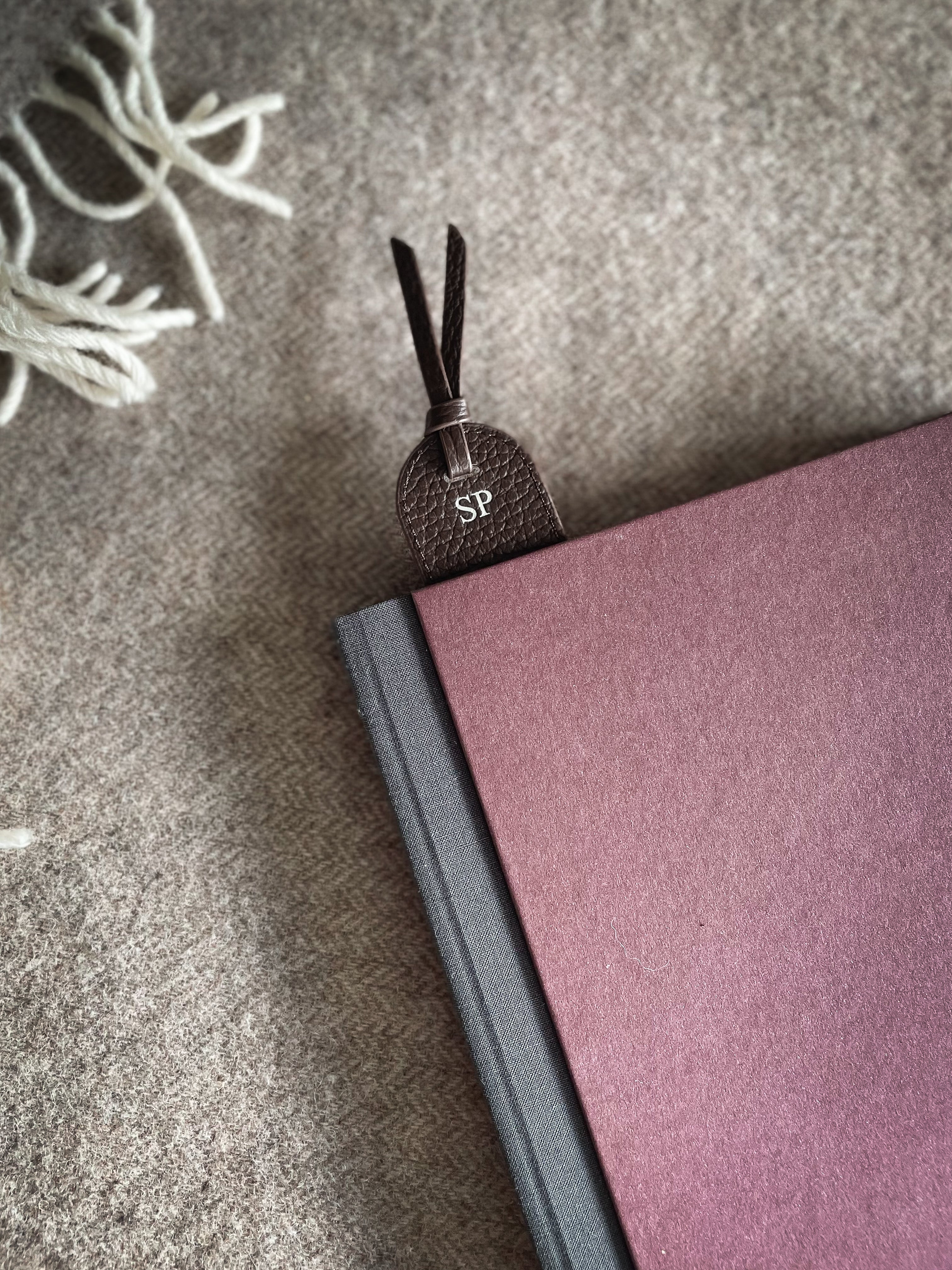 Small decorative item with initials on a purple notebook against a textured gray background