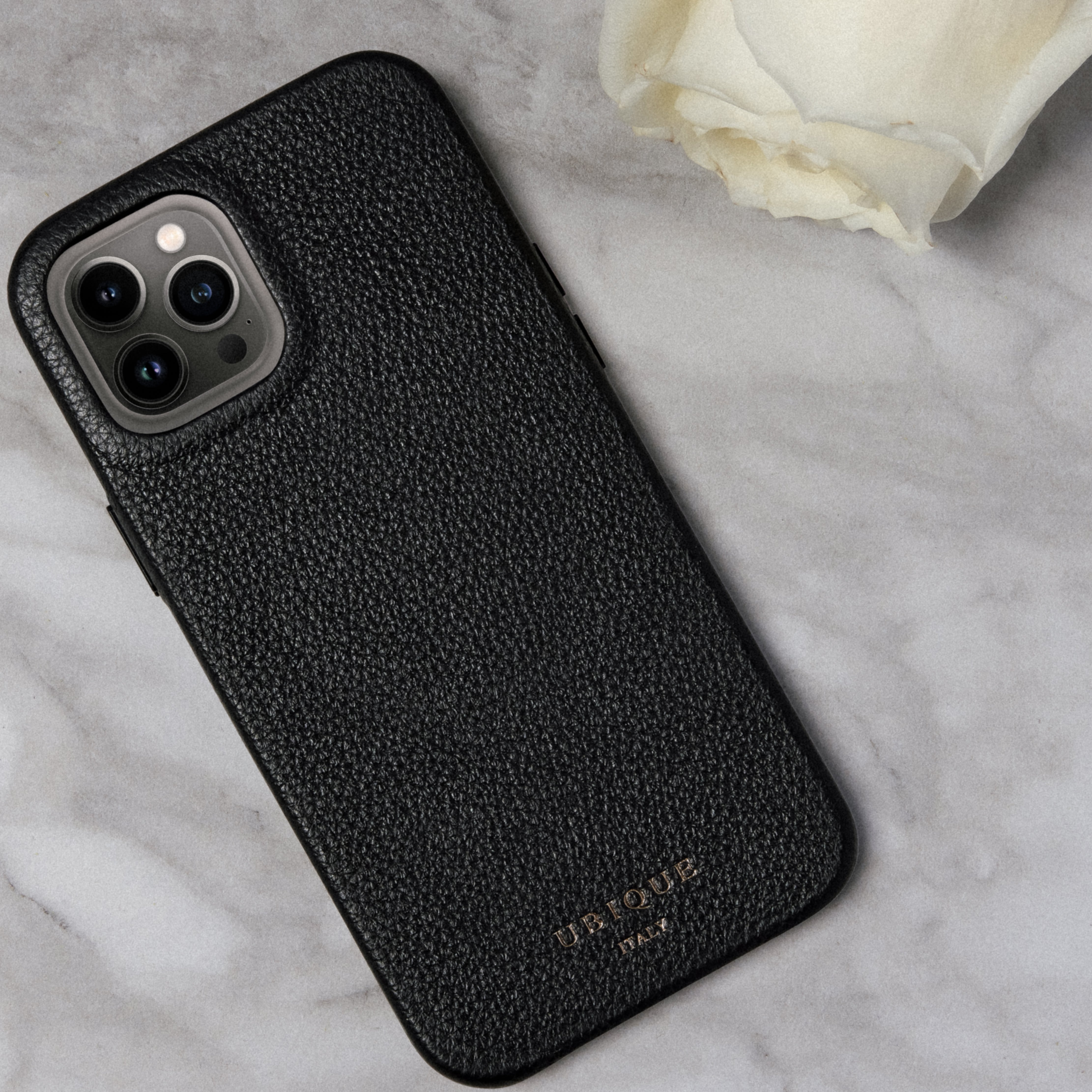 Black leather iPhone case on a white marble background with a white rose