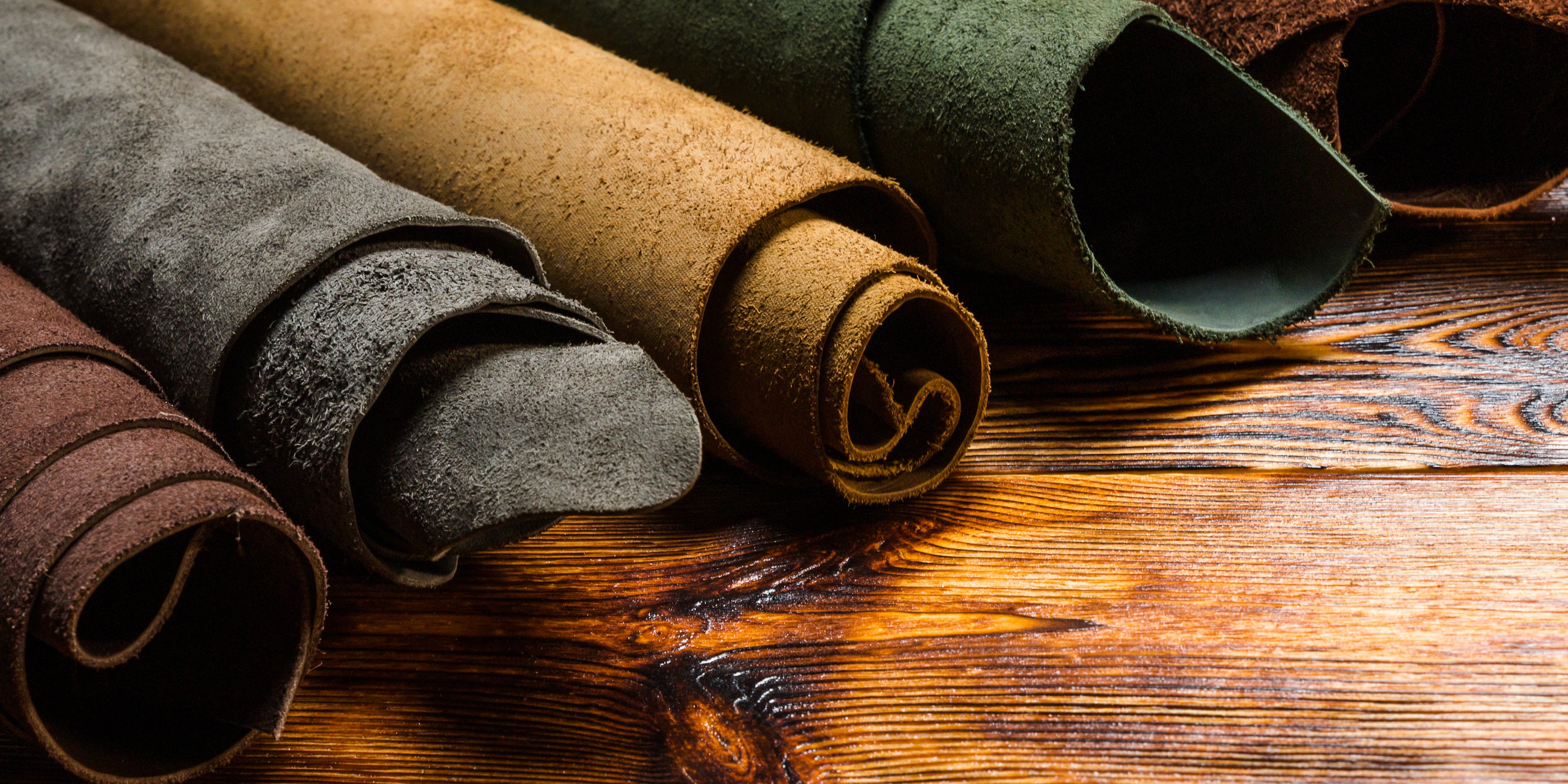 leather hides rolled up and laying on wooden table
